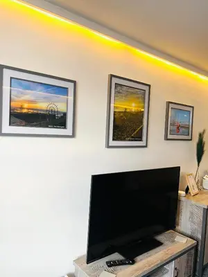 a flat screen tv on a wall with three pictures at The Annex in Southend-on-Sea