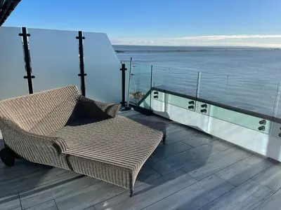 a wicker chair sitting on a deck next to the water at Seaside Luxury Retreat in Southend-on-Sea
