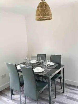 a dining room with a table with chairs and a light fixture at Modern flat near train station with free parking in Cambridge