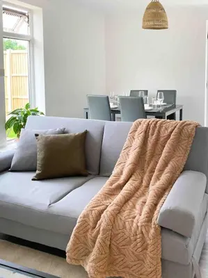 a couch with a blanket on it in a living room at Modern flat near train station with free parking in Cambridge