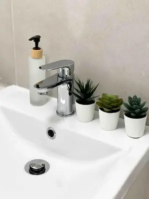a bathroom sink with three potted plants on it at Modern flat near train station with free parking in Cambridge