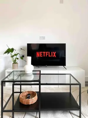a living room with a tv and a glass table at Modern flat near train station with free parking in Cambridge