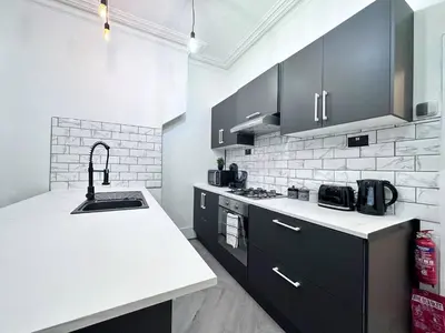 a kitchen with black cabinets and a white counter top at Swanky Seaside Sanctuary w foozeball - Southend in Southend-on-Sea