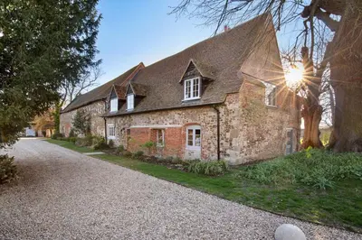 an old brick house with the sun shining on it at Bailiffs Cottage in Colchester