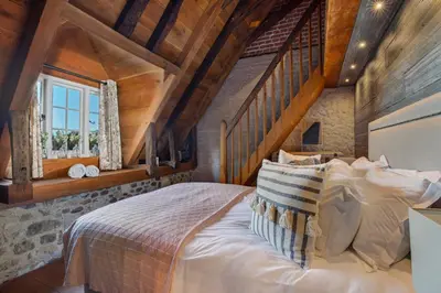 a bedroom with a large bed in a room with wooden ceilings at Bailiffs Cottage in Colchester