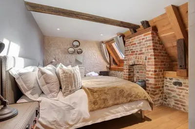 a bedroom with a bed and a brick wall at Bailiffs Cottage in Colchester
