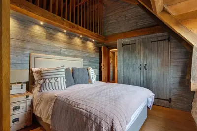 a bedroom with a bed and a wooden wall at Bailiffs Cottage in Colchester