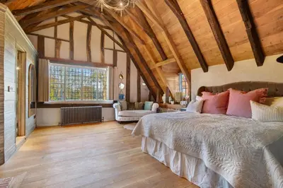 a bedroom with a large bed in a room with wooden ceilings at Bailiffs Cottage in Colchester