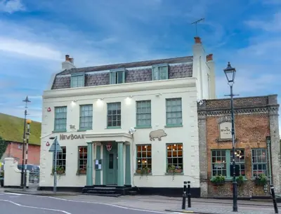 a large white building on the corner of a street at The New Boar in Theydon Bois