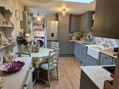 a kitchen with a table and chairs and a refrigerator at Shoemakers Cottage, Halesworth in Halesworth