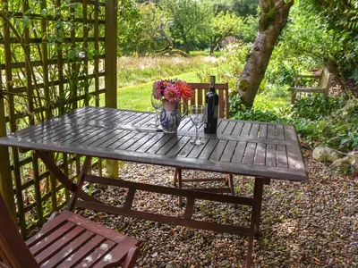 a wooden table with a vase of flowers on it at Little House On The Common in Wortham