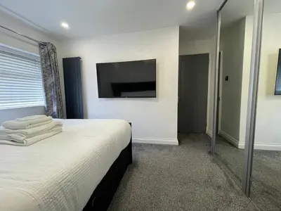 a bedroom with a bed with a television on the wall at Luxurious 2 bed home in Basildon in Basildon