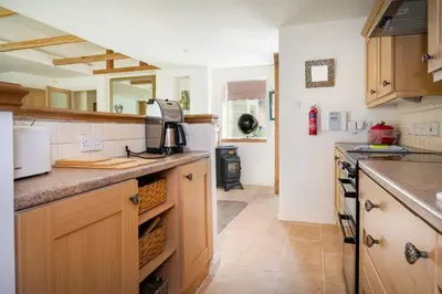 a kitchen with wooden cabinets and a counter top at The Granary at Pannels Ash Farm in Sudbury