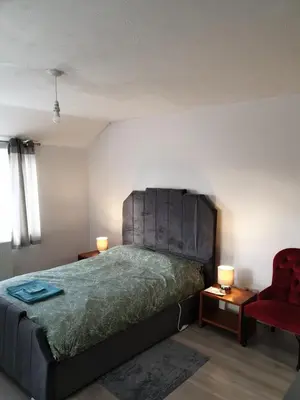 a bedroom with a bed and a red chair at Studios in Ely