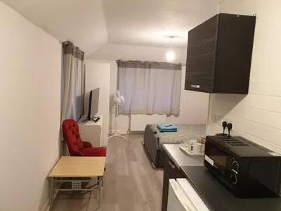 a small kitchen with a red chair in a room at Studios in Ely