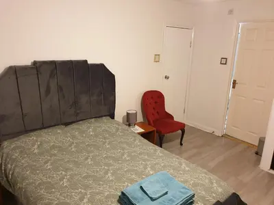a bedroom with a bed and a red chair at Studios in Ely