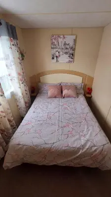 a bedroom with a large bed with a pink comforter at Modern Caravan With Wifi At Seawick holiday park, Clacton on Sea 8 berth Large Decking in Clacton-on-Sea