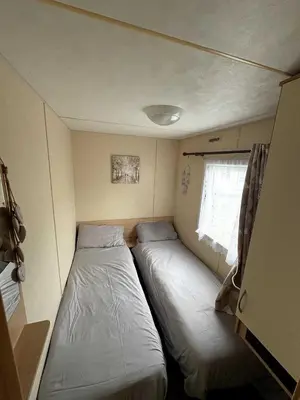 a small room with two beds and a window at Modern Caravan With Wifi At Seawick holiday park, Clacton on Sea 8 berth Large Decking in Clacton-on-Sea