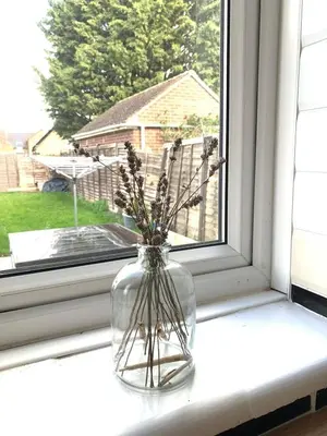 a glass vase with flowers sitting on a window sill at Contractor, families and bikes in Earith