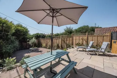 a picnic table with an umbrella and two chairs at Wonderful cottage with sun-filled terrace in Aldringham