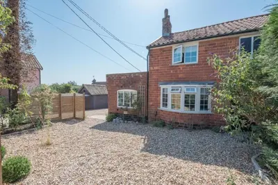 a red brick house with a gravel driveway at Wonderful cottage with sun-filled terrace in Aldringham