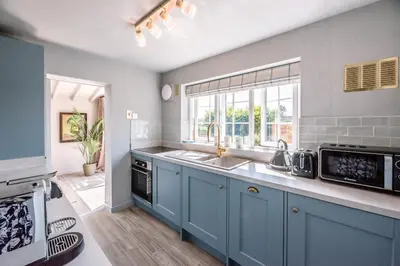 a kitchen with blue cabinets and a sink and a window at Wonderful cottage with sun-filled terrace in Aldringham
