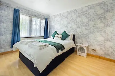 a bedroom with a large bed with blue curtains at Morden holiday in Basildon