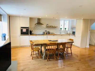 a kitchen with a wooden table and chairs at The Cottage in Birdbrook