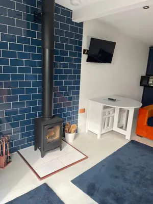 a living room with a fireplace and a blue brick wall at The Hideaway-Perfect Staycation in Belchamp Saint Paul