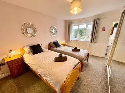 a bedroom with two beds and a window at Large 5 bed detached house near Stansted Airport with Parking for 2 vehicles! Stansted Stays in Stansted Mountfitchet