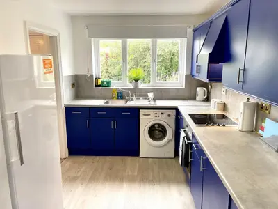 a kitchen with blue cabinets and a washing machine at Large 5 bed detached house near Stansted Airport with Parking for 2 vehicles! Stansted Stays in Stansted Mountfitchet