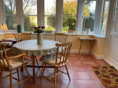a dining room with a table and chairs and windows at Peaceful house ideal for dogs lovely location in Aldeburgh