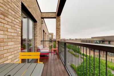 a balcony with a bench and chairs on a brick building at Pass the Keys Stunning and Spacious Modern Flat - Own Car Park in Cambridge