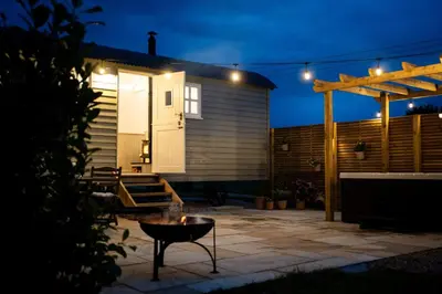 a tiny house with a patio at night at The Huts At Woodthorpes in Assington