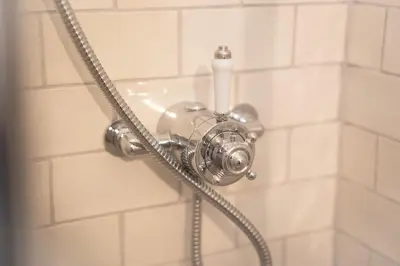 a shower head with a hose in a bathroom at The Huts At Woodthorpes in Assington