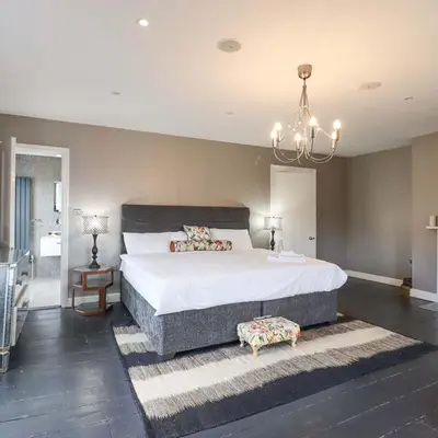a large bedroom with a large bed and a chandelier at Luxury Georgian House With Sauna Sleeps 19-23 in Harleston
