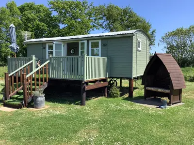 a green tiny house with a ramp and a play structure at Muffins Meadow Shepherds Hut in Tillingham
