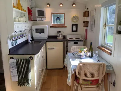 a small kitchen with a table and a table and chairs at Muffins Meadow Shepherds Hut in Tillingham