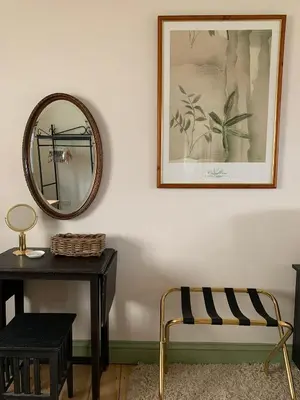 a mirror on a wall next to a table and a chair at Hidden gem in heart of Breckland in Watton