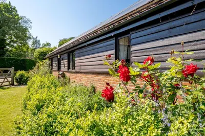 a house with red flowers in front of it at 1 Bed in Saxmundham oc-c27420 in Farnham