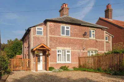 a red brick house with a wooden fence at Hole in One in Aldeburgh