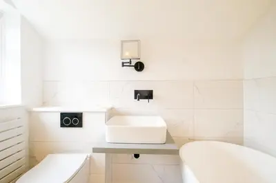 a white bathroom with a sink and a mirror at Hole in One in Aldeburgh