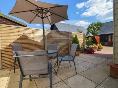 a table and chairs with an umbrella on a patio at Wellington Cottage in Ely