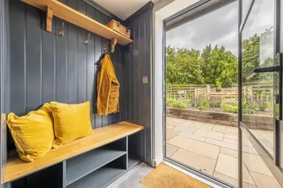 a room with a bench and a sliding glass door at Granary Cottage in Wenhaston