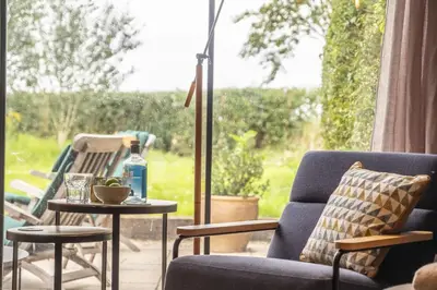 a living room with a chair and a table and a window at Granary Cottage in Wenhaston