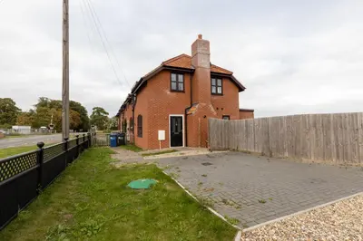 a brick house with a fence in front of it at The Poppies Cottage in Six Mile Bottom