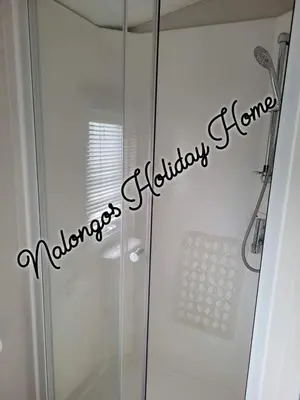 a shower stall with a glass door with the words laundry etiquettetheme at FV006 NALONGOS HOLIDAY HOME in Saint Osyth