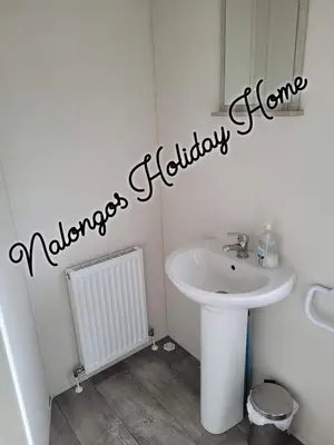 a bathroom with a sink and a mirror at FV006 NALONGOS HOLIDAY HOME in Saint Osyth