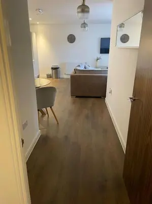 a hallway to a living room with a sink and a couch at Spacious Apartment in the Heart of Chelmsford in Chelmsford