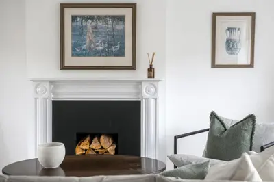 a living room with a fireplace and a table at Luxurious 3 Bed House with Free Parking, Sky TV, Movies & Netflix in Braintree
